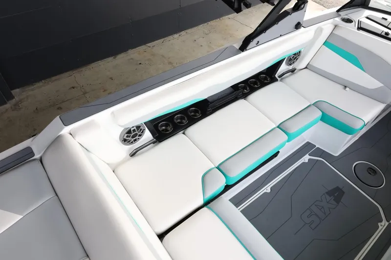 Slide: The Image of 2023 Axis T220 boat interior with white and teal seating, cup holders, and speakers. - 13