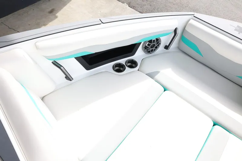 Slide: The Image of 2023 Axis T220 boat interior with white seating, teal accents, and cup holders. - 17