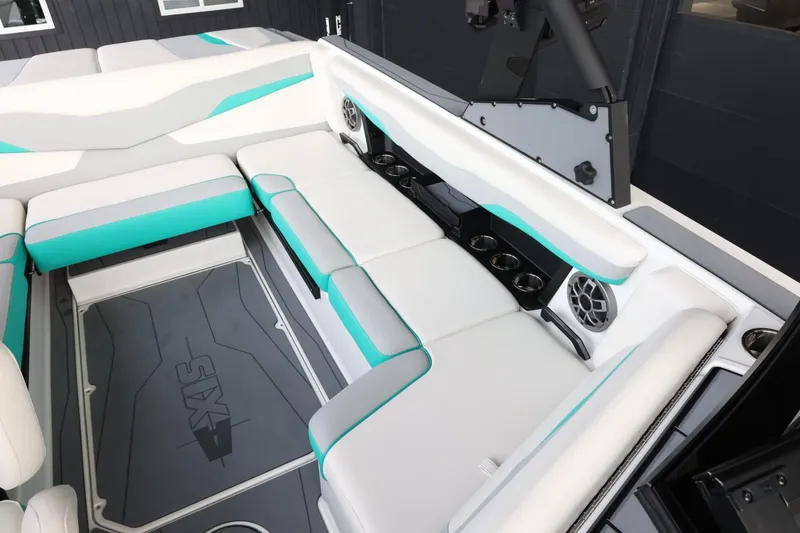 Slide: The Image of 2023 Axis T220 boat interior with white and teal seating, cup holders, and speakers. - 21