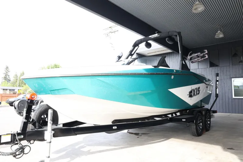Slide: The Image of 2023 Axis T220 boat in teal, parked on a trailer under a covered area. - 4