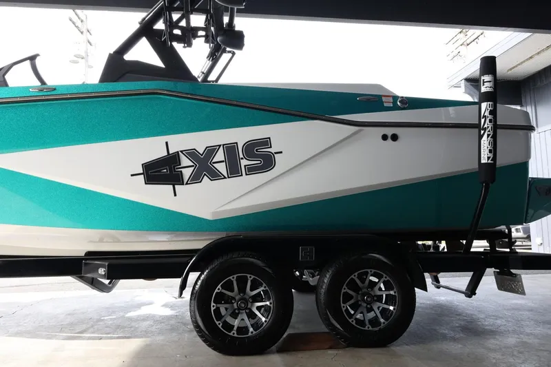 Slide: The Image of 2023 Axis T220 boat on trailer, teal and white design, side view. - 5