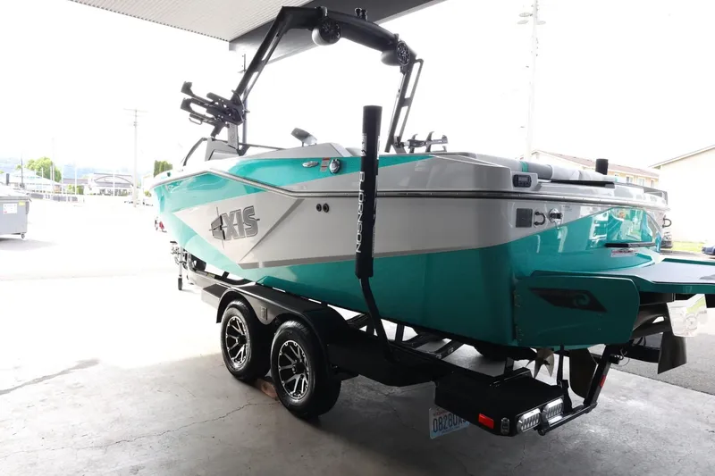 Slide: The Image of 2023 Axis T220 boat in teal and white on a trailer, parked indoors. - 6
