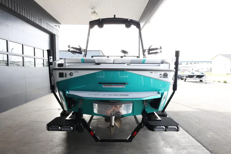 Slide: The Image of 2023 Axis T220 boat, rear view, teal color, parked in a covered area. - 7