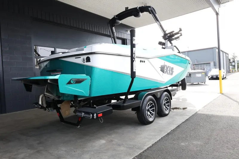 Slide: The Image of 2023 Axis T220 boat on trailer, teal and white design, parked under a canopy. - 8