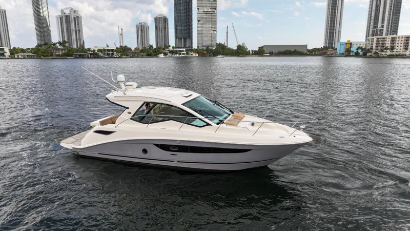 Slide: The Image of 2017 Sea Ray 350 Coupe yacht cruising on urban waterfront with skyscrapers in background. - 2