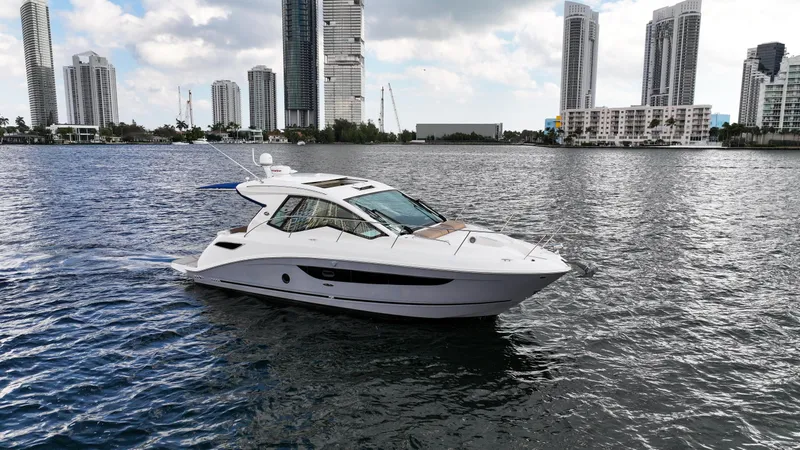 Slide: The Image of 2017 Sea Ray 350 Coupe cruising on water with city skyline backdrop. - 3