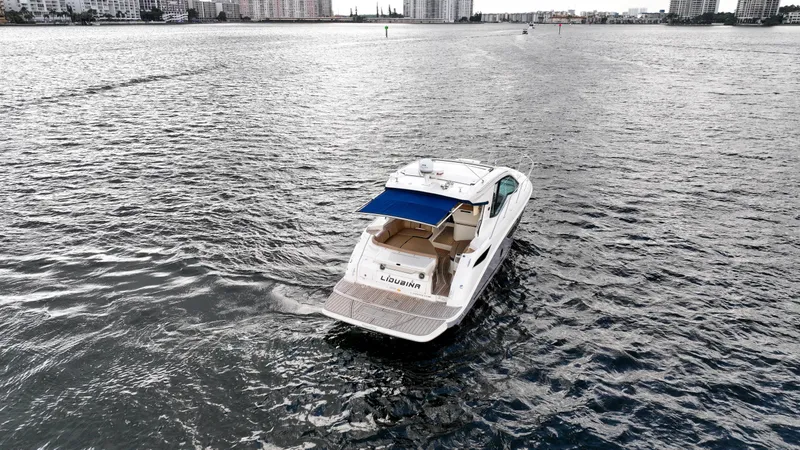 Slide: The Image of 2017 Sea Ray 350 Coupe cruising on open water with city skyline in background. - 6