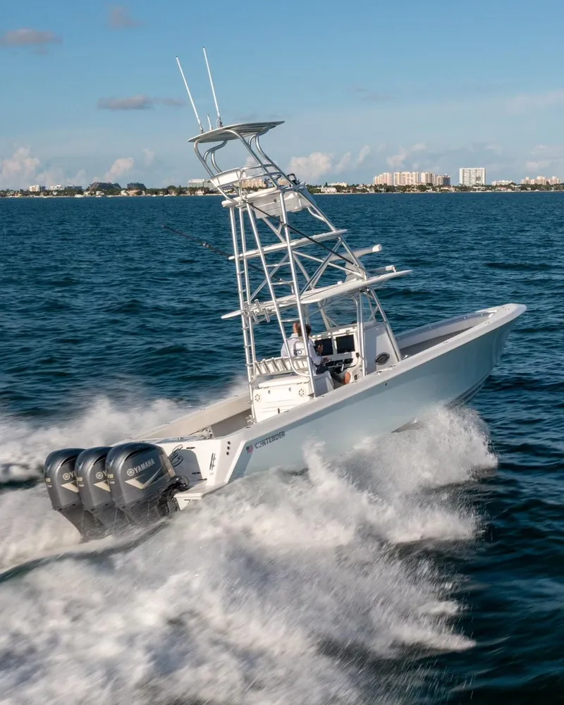 Slide: The Image of 2018 Contender 39 ST boat cruising on open water with triple outboard engines. - 11