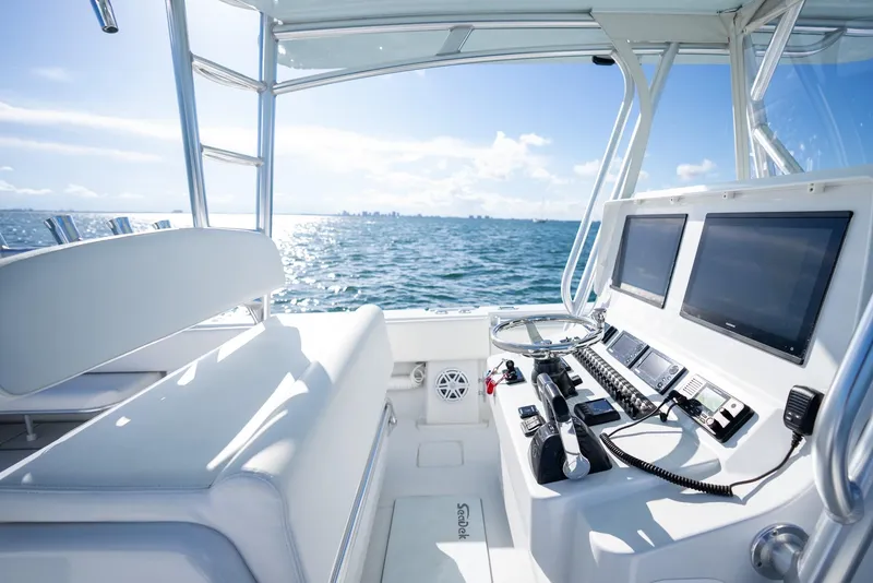 Slide: The Image of 2018 Contender 39 ST boat interior with dual screens, steering wheel, and ocean view. - 19