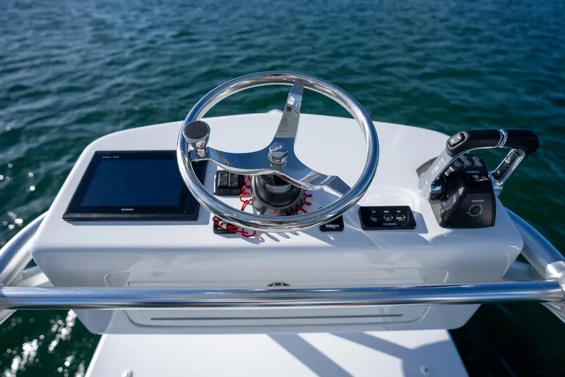 Slide: The Image of 2018 Contender 39 ST boat helm with steering wheel, controls, and navigation screen on open water. - 28