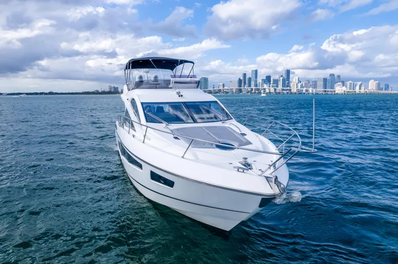 Slide: The Image of 2016 Sunseeker Manhattan 55 yacht cruising on open water with city skyline backdrop. - 18