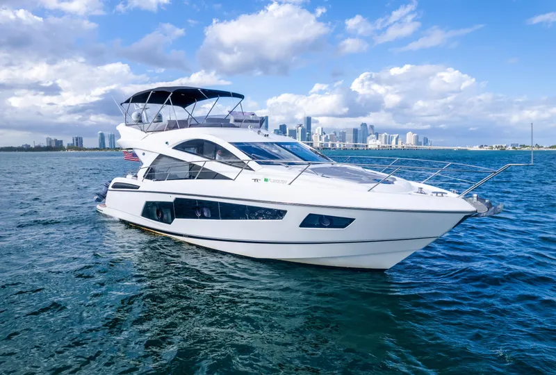 Slide: The Image of 2016 Sunseeker Manhattan 55 yacht cruising on open water with city skyline backdrop. - 5