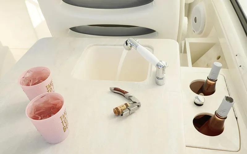 Slide: The Image of 2025 Cobia 280 DC boat interior with sink, drinks, and corkscrew on counter. - 23