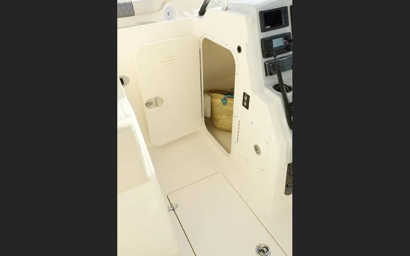 Slide: The Image of 2025 Cobia 280 DC boat interior storage compartment with basket and control panel. - 24