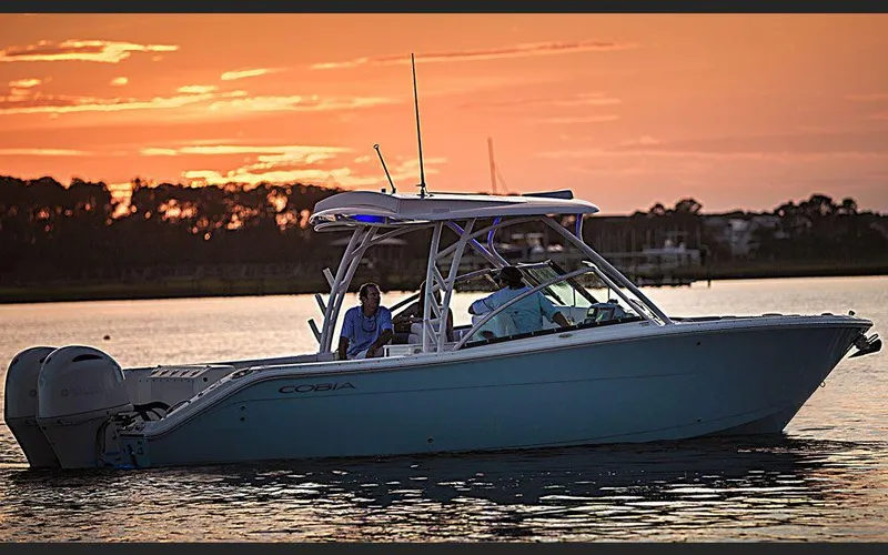 Slide: The Image of 2025 Cobia 280 DC boat cruising at sunset on calm waters. - 3