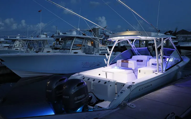 Slide: The Image of 2025 Cobia 280 DC boat illuminated at night, docked with Yamaha engines. - 4
