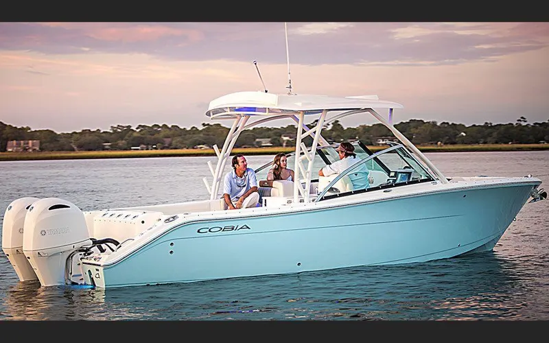 Slide: The Image of 2025 Cobia 280 DC boat cruising on serene waters at sunset. - 5