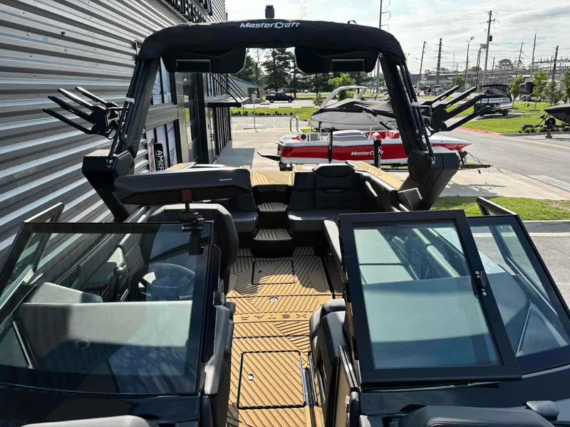 Slide: The Image of 2025 MasterCraft XSTAR23 boat with sleek design and modern features, docked outdoors. - 13