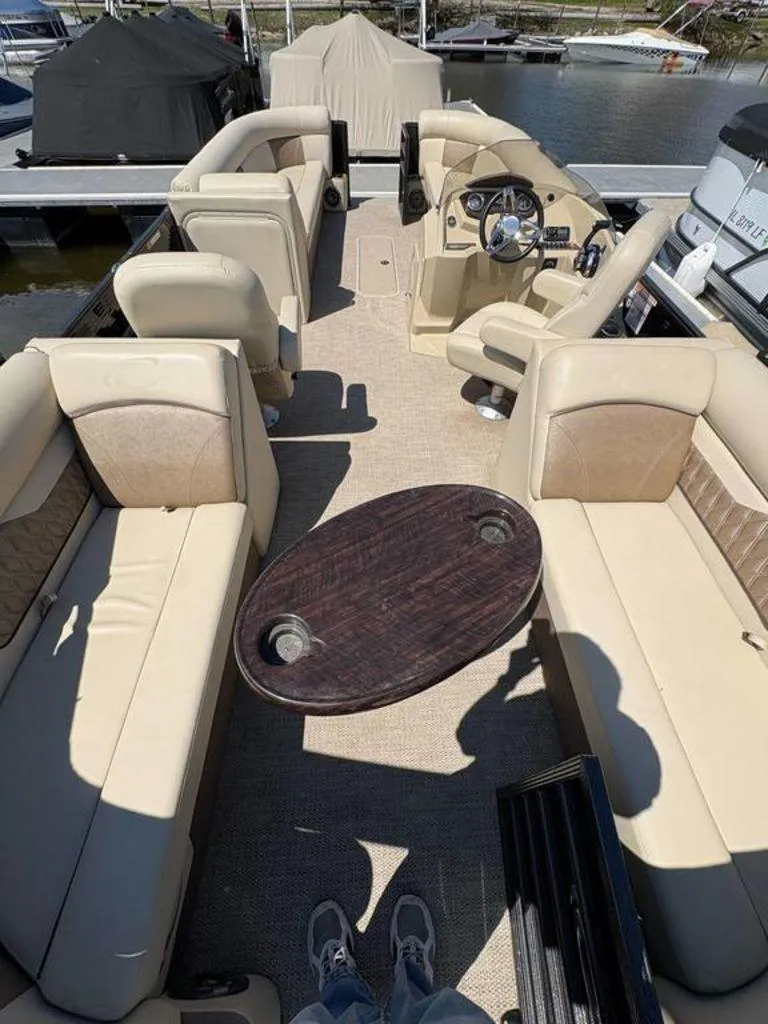 Slide: The Image of 2020 Crest Classic DLX 240 SLC pontoon boat interior with beige seating and wooden table. - 12