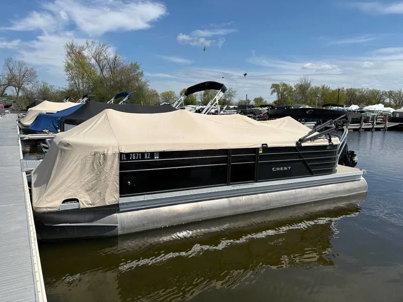 Slide: The Image of 2020 Crest Classic DLX 240 SLC pontoon boat docked with cover, under clear sky. - 14