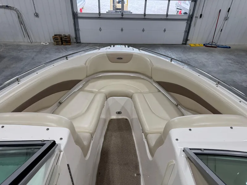Slide: The Image of 2005 Chaparral 256 SSi boat interior with beige seating and carpeted floor in a garage. - 11