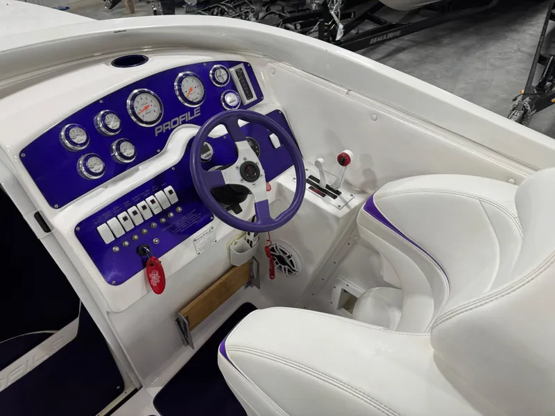 Slide: The Image of Cockpit of a 2003 Profile 290 boat with purple dashboard and white seating. - 10