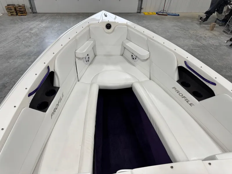 Slide: The Image of 2003 Profile 290 boat interior with white seating and cup holders in a garage setting. - 16