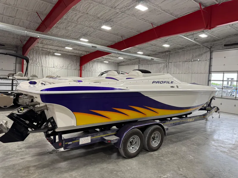 Slide: The Image of 2003 Profile 290 boat with vibrant blue and yellow design in a spacious indoor facility. - 3