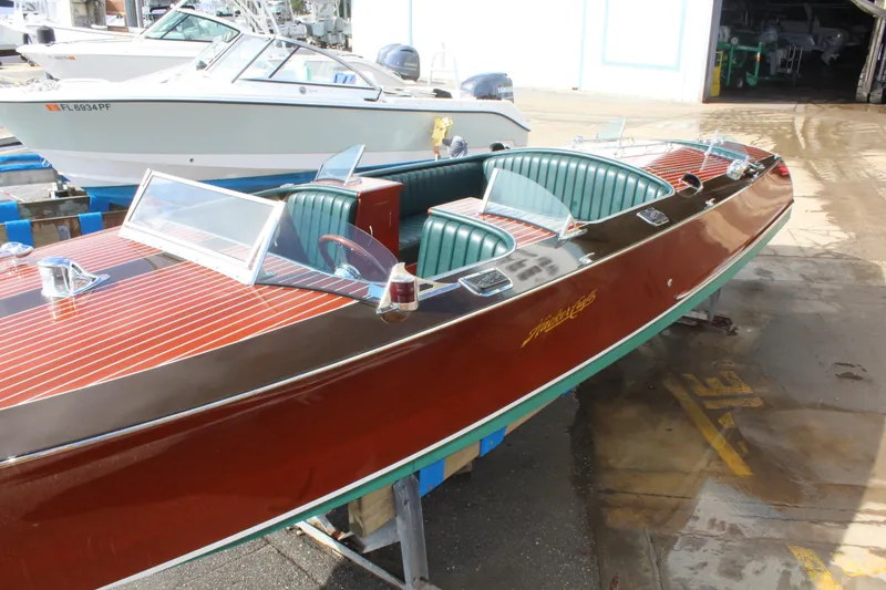 Slide: The Image of 2017 Hacker-Craft 30 boat with polished wood finish and green interior, docked at a marina. - 17