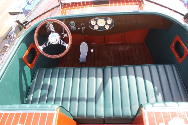 Slide: The Image of 2017 Hacker-Craft 30 boat interior with green leather seats and wooden dashboard. - 8