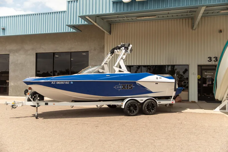 Slide: The Image of 2015 Axis 22 boat in blue and white on a trailer outside a building. - 1