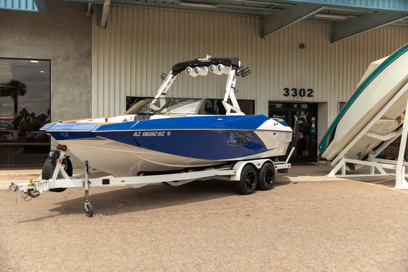 Slide: The Image of 2015 Axis 22 boat on trailer outside a building, showcasing sleek design and vibrant blue color. - 2