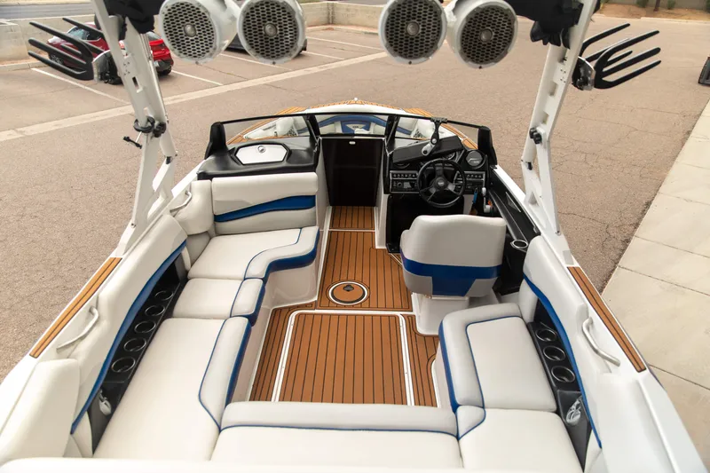 Slide: The Image of 2015 Axis 22 boat interior with white and blue seating, wood flooring, and mounted speakers. - 4