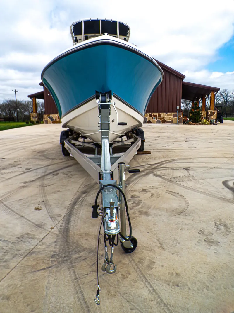 Slide: The Image of 2025 Mako 214CC boat on trailer, parked outdoors, front view. - 3