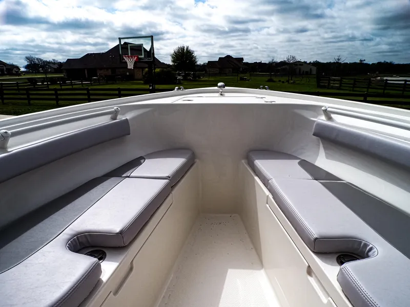 Slide: The Image of 2025 Mako 214CC boat interior with cushioned seating, set against a suburban backdrop. - 8