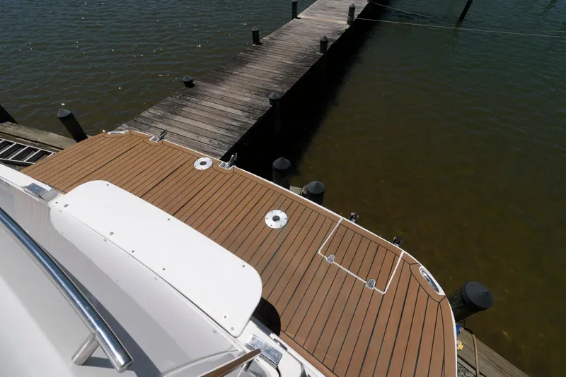 Slide: The Image of 2006 Rinker 390 Express Cruiser docked, featuring a wooden deck and calm waters. - 11