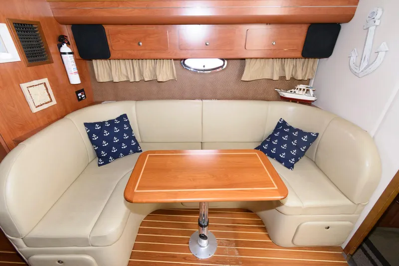 Slide: The Image of 2006 Rinker 390 Express Cruiser interior with beige seating, wooden table, and nautical decor. - 13