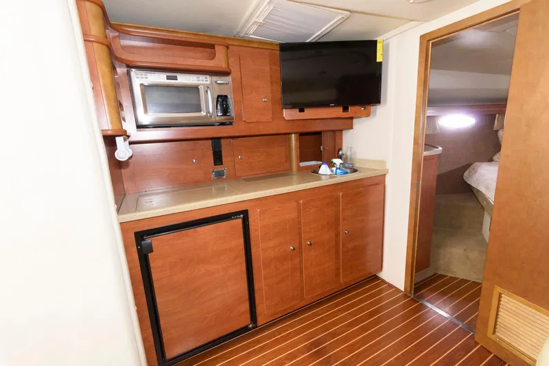 Slide: The Image of 2006 Rinker 390 Express Cruiser interior with kitchenette, microwave, TV, and wood flooring. - 14