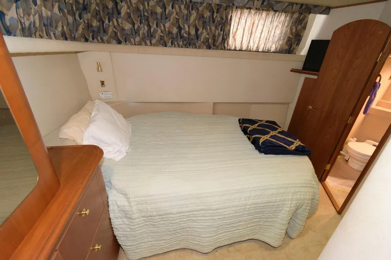 Slide: The Image of 1999 Cruisers Yachts 3750 Motoryacht bedroom with bed, dresser, and ensuite bathroom. - 23