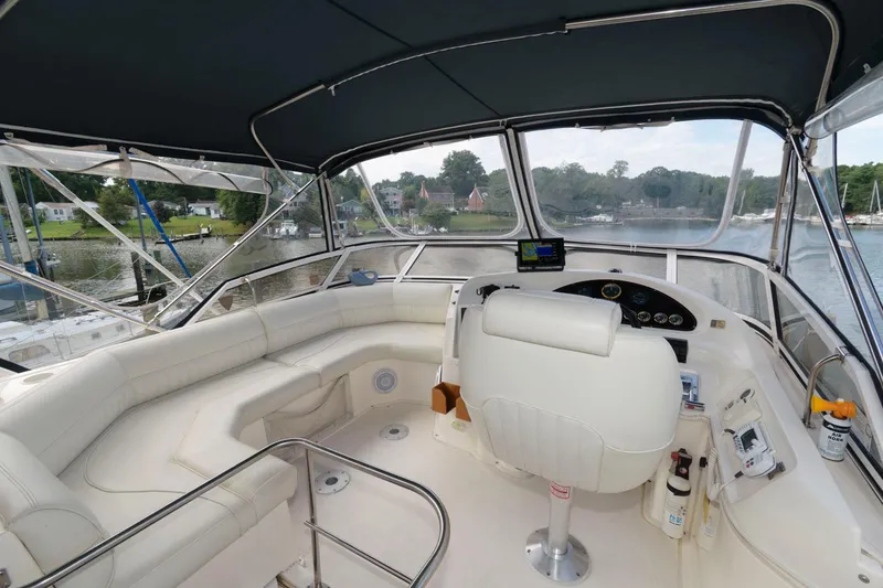 Slide: The Image of 1999 Cruisers Yachts 3750 Motoryacht helm with seating, overlooking serene waterfront. - 5