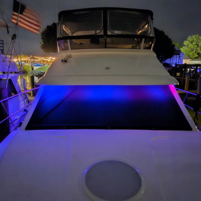 Slide: The Image of 1999 Cruisers Yachts 3750 Motoryacht with vibrant blue and purple lights at night. - 16