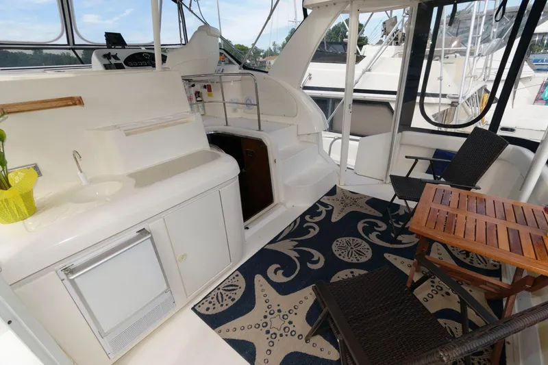 Slide: The Image of 1999 Cruisers Yachts 3750 Motoryacht interior with seating, table, and nautical-themed rug. - 2