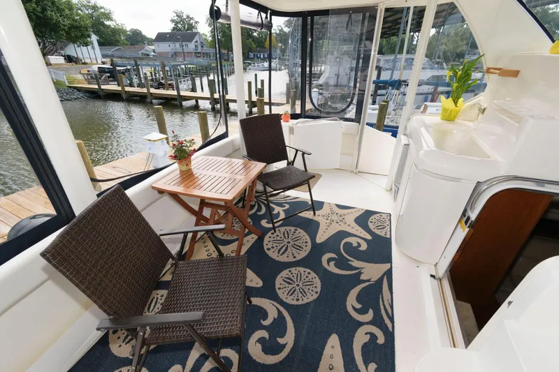 Slide: The Image of 1999 Cruisers Yachts 3750 Motoryacht deck with chairs, table, and nautical-themed rug. - 3