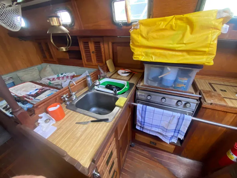 Slide: The Image of 1983 Shannon 38 sailboat galley with sink, stove, and wooden cabinetry. - 11