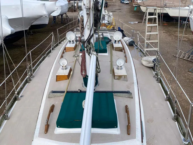 Slide: The Image of 1983 Shannon 38 sailboat deck with green covers and rigging, docked on land. - 13