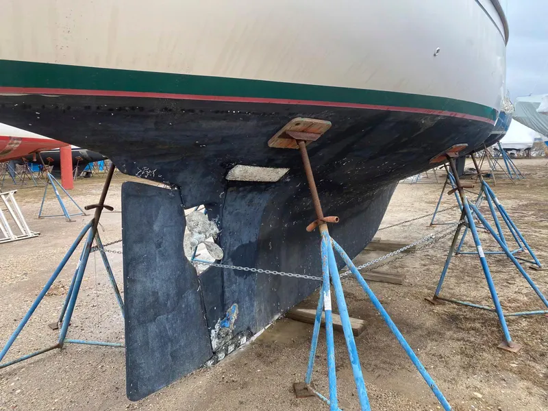 Slide: The Image of 1983 Shannon 38 sailboat on stands, showing hull and keel damage. - 20