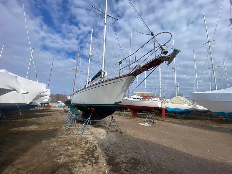 Slide: The Image of 1983 Shannon 38 sailboat on stands in a boatyard under a cloudy sky. - 6