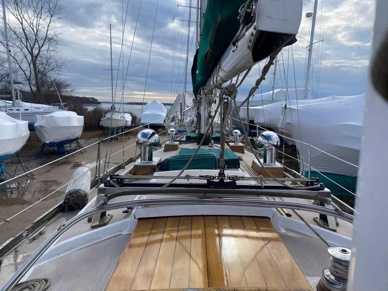 Slide: The Image of 1983 Shannon 38 sailboat on land, surrounded by covered boats, under a cloudy sky. - 7