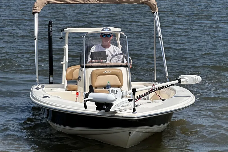 Slide: The Image of 2020 Scout 177 Sport boat on water with canopy and driver. - 2