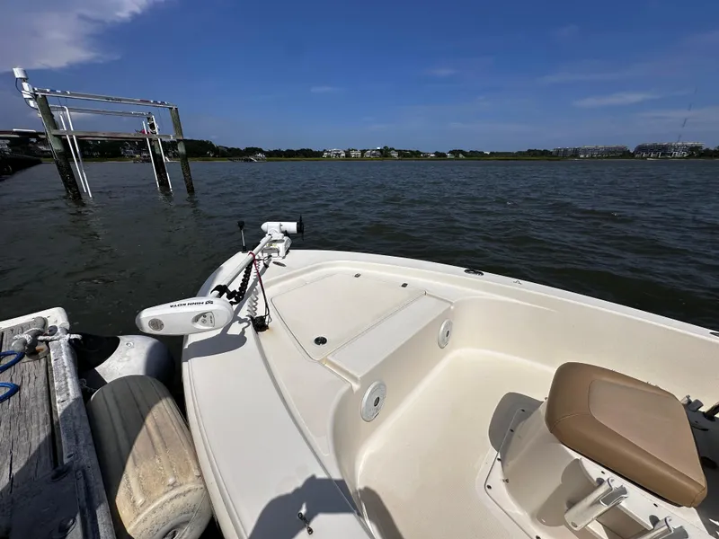 Slide: The Image of 2020 Scout 177 Sport boat docked by a calm lake under a clear blue sky. - 8